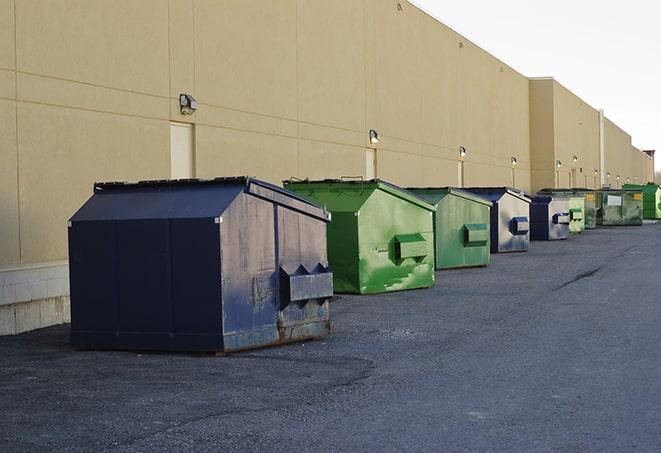 a construction worker unloading debris into a blue dumpster in Clinton WI